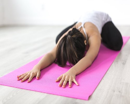 Person doing soft stretching on a yoga mat at home